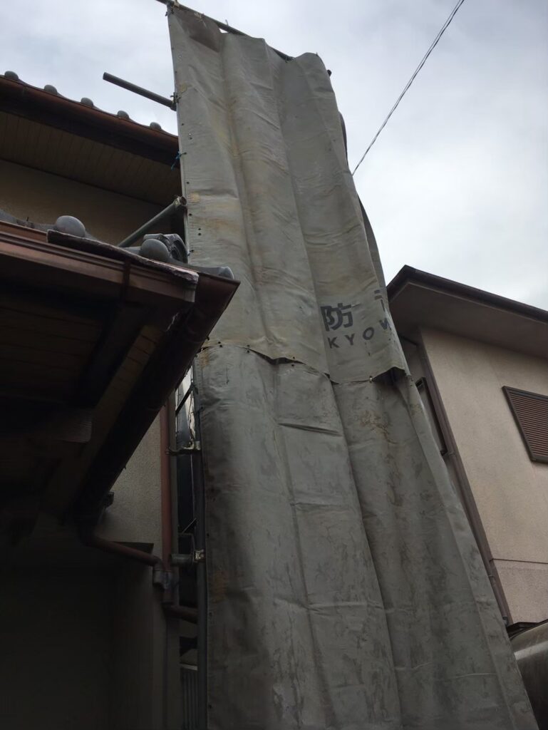 解体工事前に隣家との距離が近い箇所を養生シートで覆い、粉じんや破片の飛散を防止している屋内準備の様子①